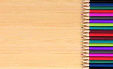 Fototapeta premium Colored pencils on wooden board for background