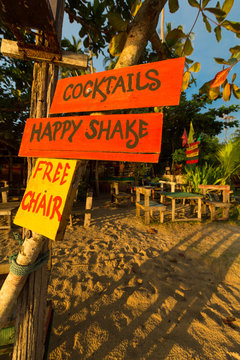 Orange and yellow signs on the beach offering cocktails and chai