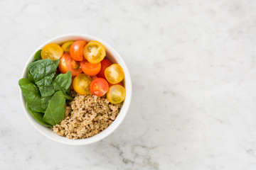 Quinoa with vegetables on white marble table
