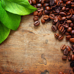 Obraz na płótnie Canvas Coffee on wooden background with green leaves