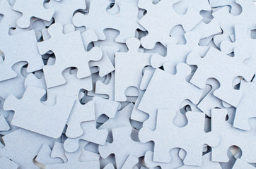 Pile of grey blank puzzle pieces background.