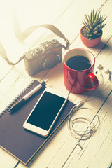 Cup of coffee, smart phone, notebook, pen, camera,earphone and c