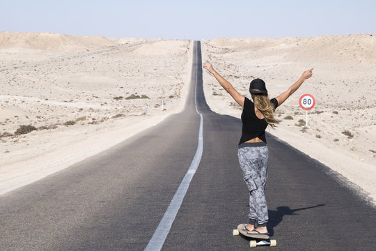Woman practicing longboard in long way. Dakhla, Morocco.