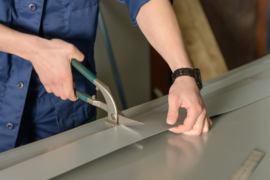 Man cuts metal sheet with a cutter