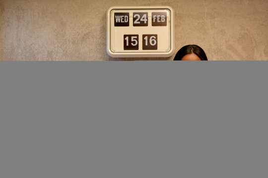 Woman beside flip clock looking at camera smiling