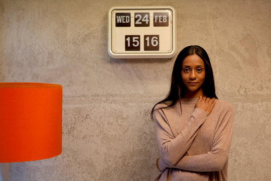 Woman beside flip clock looking at camera smiling