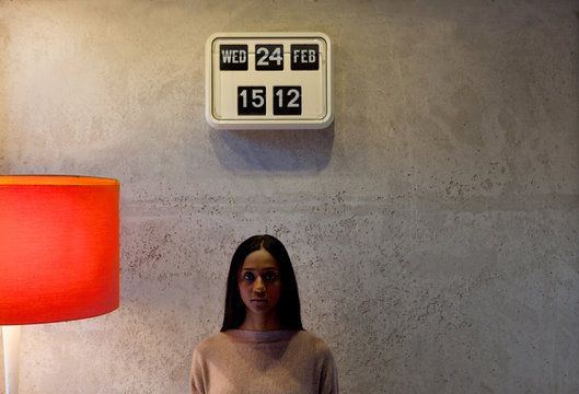 Woman underneath flip clock looking at camera