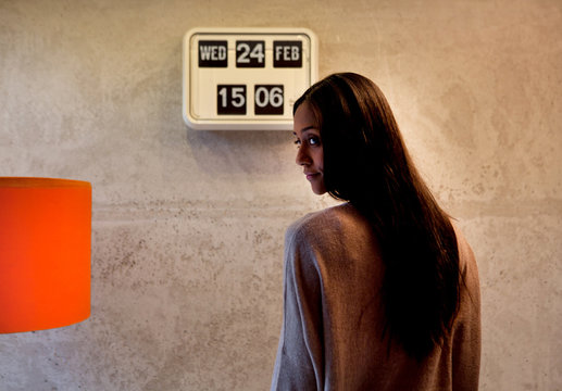 Rear view of woman in front of flip clock looking away over shoulder