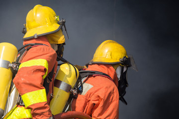 Fototapeta premium 2 firefighters in operation and dark smoke background