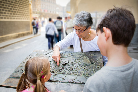 Senior woman and grandchildren pointing at city map, Florence, Italy