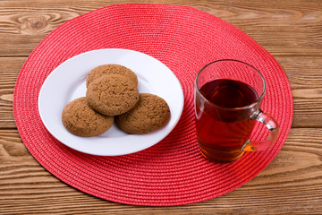 Oatmeal cookies on a plate and cup of tea on a wooden background 