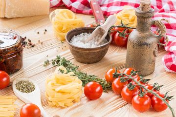 cherry tomatoes fruits, dried tomatoes in glass jar on wooden table, herbs, basil leaf,  thyme, , pasta, fidelini,  spaghetti, olive oil in clay jug, italian food concept