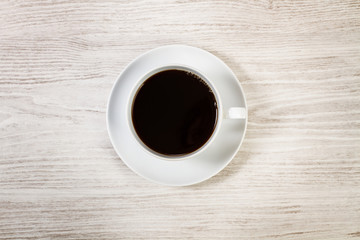 Taza de café vista desde arriba sobre tabla de madera blanca. Copy space