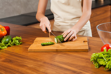 Close up picture of young lady's hands cutting cucumber