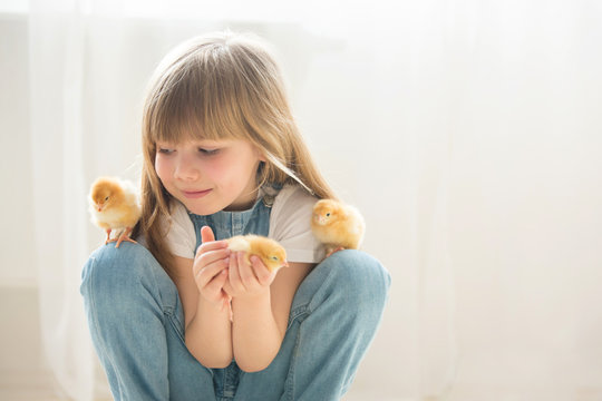 Young beautiful girl, playing with little newborn chick at home