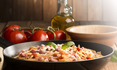 Spaghetti with amatriciana sauce in the pot on the wooden table