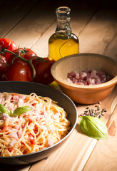 Spaghetti with amatriciana sauce in the pot on the wooden table