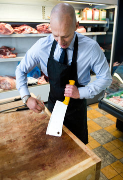Butcher cleaning meat cleaver in butcher's shop