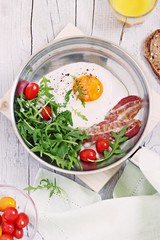 Fried egg with bacon,arugula and tomatoes.