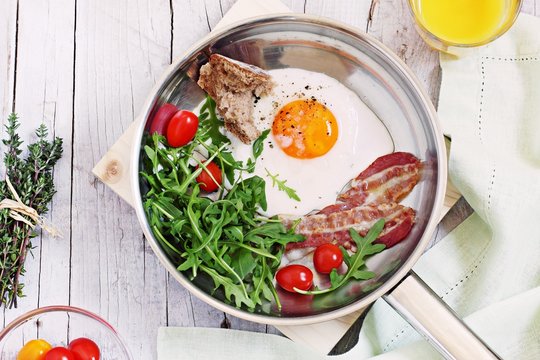 Fried egg with bacon,arugula and tomatoes.