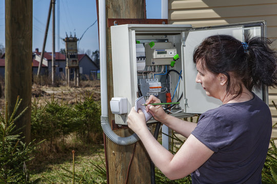 Rural adult women to take readings of electricity meter outdoors