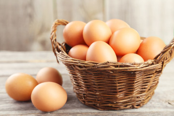 Chicken eggs in basket on grey wooden background