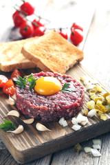 Beef tartare with egg yolk on a grey wooden table