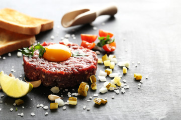 Beef tartare with egg yolk on a black wooden table