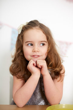 Girl with bunny teeth daydreaming at table