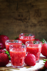 Freshly squeezed strawberry juice in a small glass and a large f