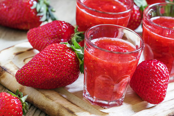 Freshly squeezed strawberry juice in a small glass and a large f