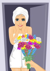 Surprised young woman wrapped in white towel receiving bouquet of flowers from men's hand next to open door