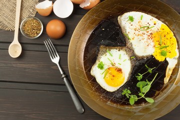 Fried fried egg on steel pan. Preparing homemade dietary supplements. Pan on a dark wooden table. Fried eggs.
