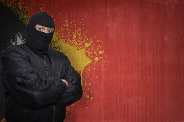 dangerous man in a mask standing near a wall with painted national flag of east timor