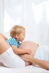 Kid boy hugging pregnant mother's belly