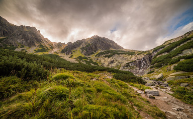 Mountain Landscape with Skok Waterfall under Dramatic Glowing Sky and Sun Shining From Behind the Peaks. Mlynicka Valley, High Tatra, Slovakia. © kaycco