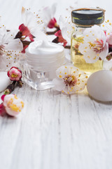 Face cream, fragnat oil and decorative stone with blossom on rustic wooden background