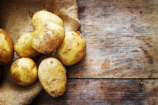 Raw potatoes on wooden background