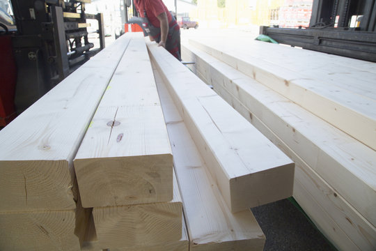 Male warehouse worker stacking wooden planks for hardware store