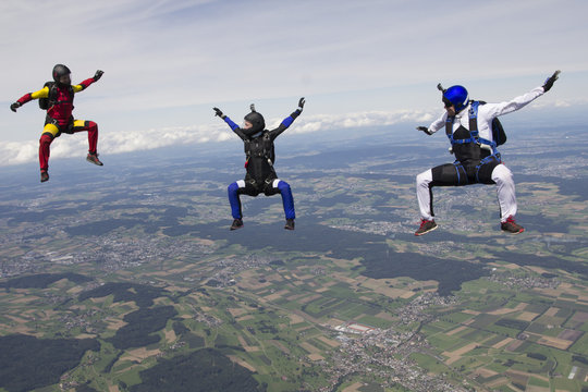 Team of three skydivers in sit fly position