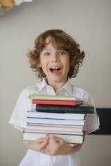 The boy holds a stack of books