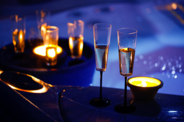 Candlelit champagne glasses beside a jacuzzi