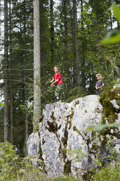 Brother and sister playing on rock formation in forest, Zauberwald, Bavaria, Germany