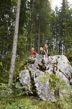 Brother and sisters playing on rock formation in forest, Zauberwald, Bavaria, Germany