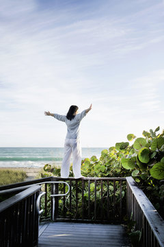 Mature woman with arms open on top of walkway railing, Juno Beach, Florida, USA