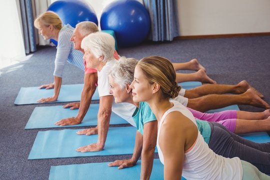 Fototapeta Seniors and fitness instructor stretching their legs