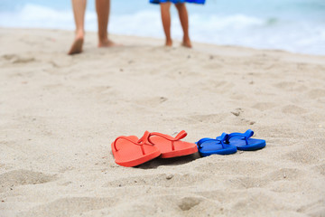 Fototapeta na wymiar father and son walking at beach, flip flops on sand