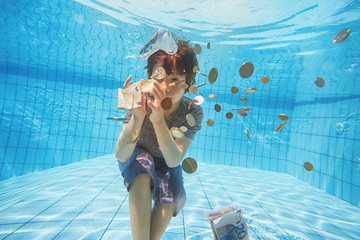 Underwater view of boy grabbing euro currency in swimming pool