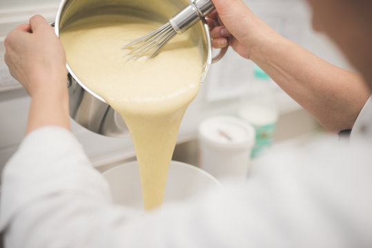 Baker pouring mixture into bowl in kitchen