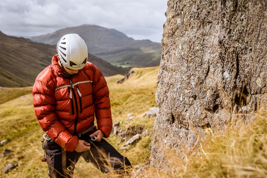 Young male climber fastening rope, The Lake District, Cumbria, UK